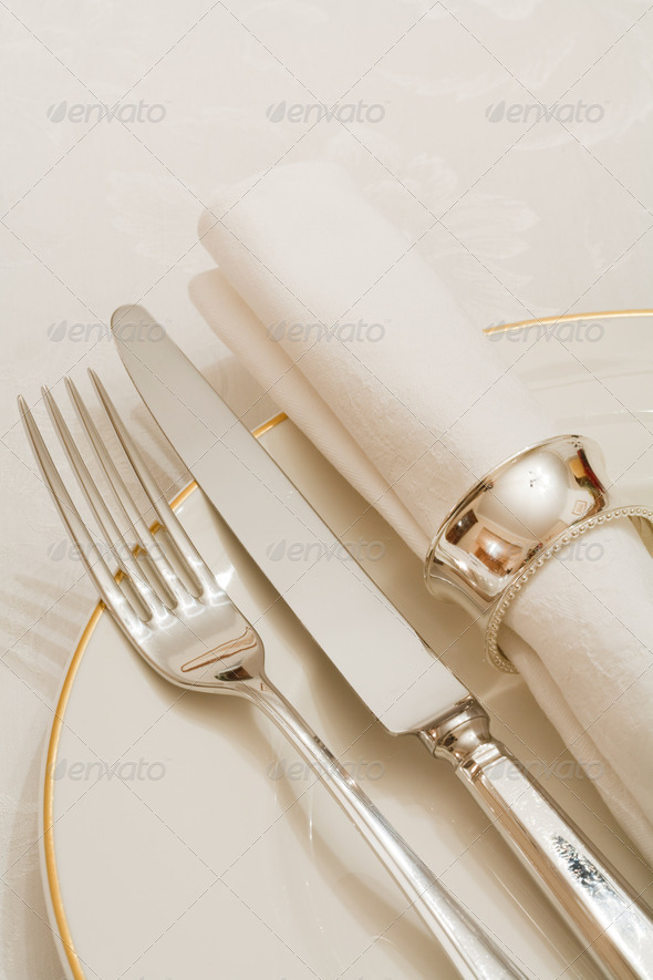 Place setting with cutlery, plate and napkin on a damask tablecloth