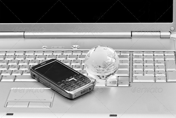 Mobile phone and glass globe on laptop keyboard. Black & White i - Stock Photo - Images