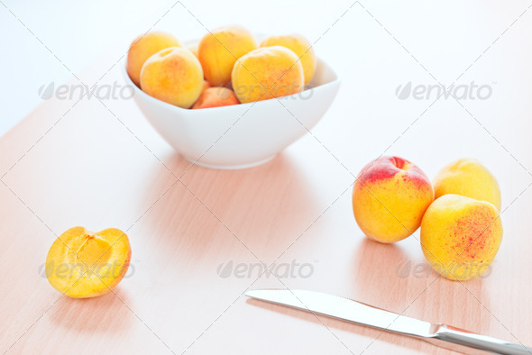 Fresh Apricots and a table knife on kitchen wooden background - Stock Photo - Images