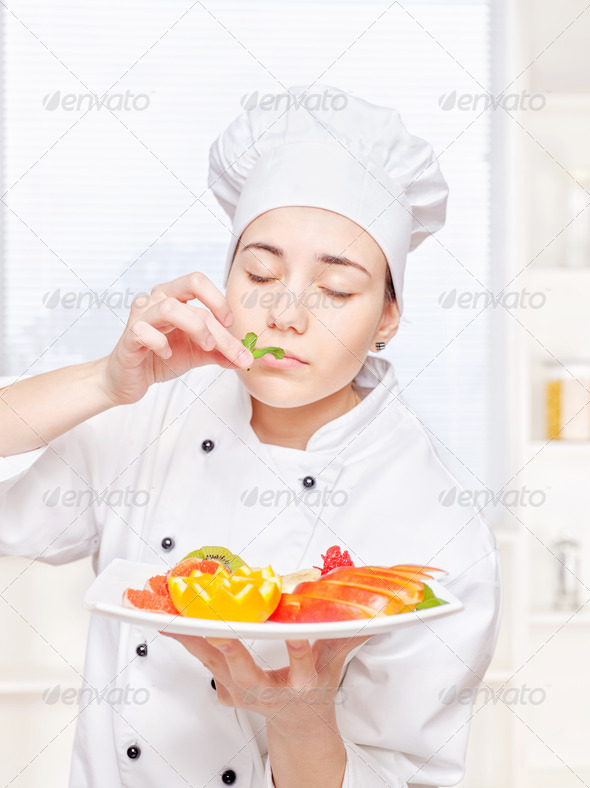 chef smell mint before putting it on a plate of fruit - Stock Photo - Images