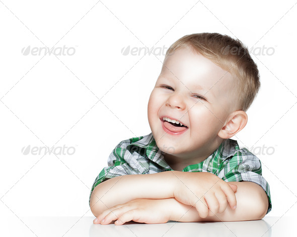 Portrait of a cute little boy smiling while sitting at table, is - Stock Photo - Images