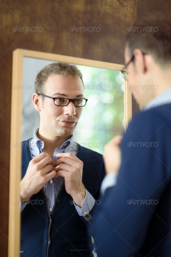 Young man dressing up and looking at mirror - Stock Photo - Images