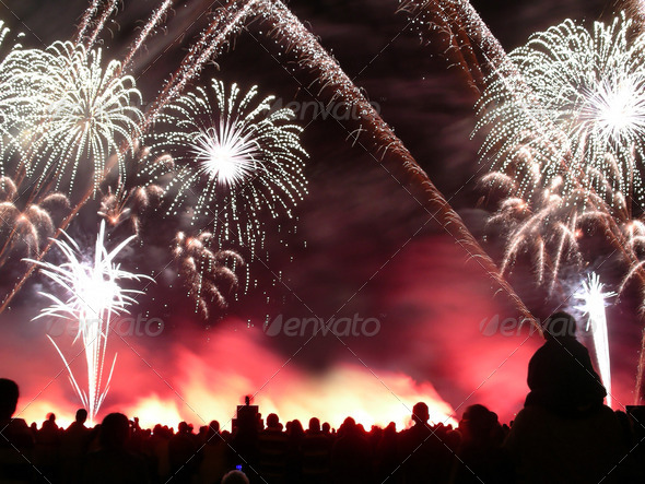 Fireworks in a fireworks contest with a silhouetted crowd watching in the foreground.