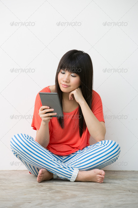 Young Asian girl sitting holding a Reader. - Stock Photo - Images
