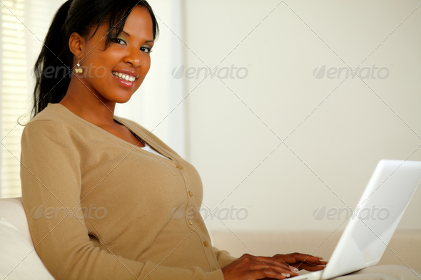 Pretty girl smiling at you while working on laptop - Stock Photo - Images