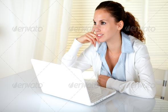Pensive young woman in front of her laptop - Stock Photo - Images
