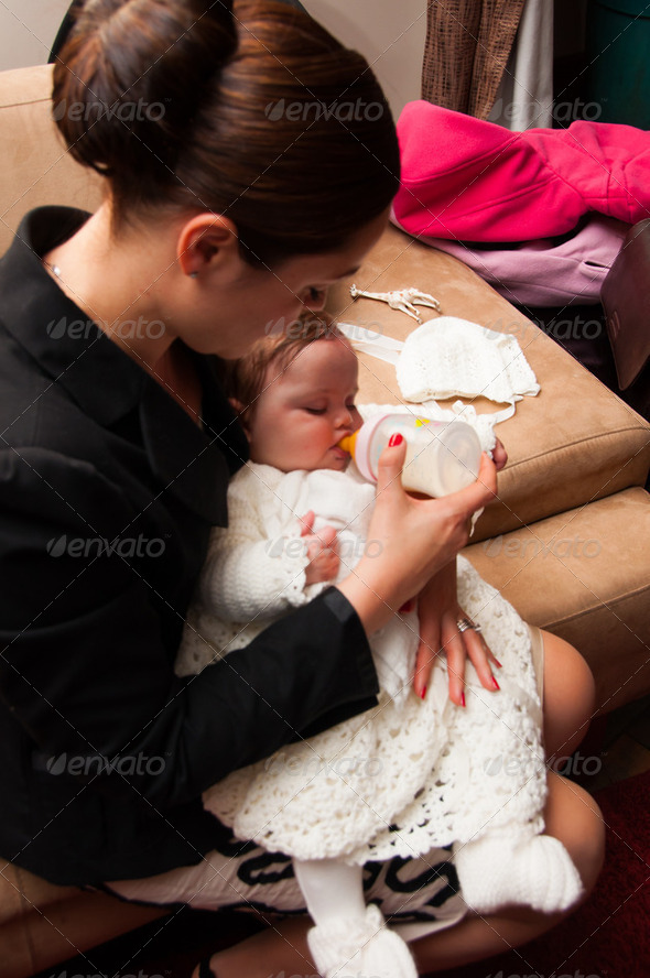 Young mother feeding baby girl on her lap from a milk bottle - Stock Photo - Images