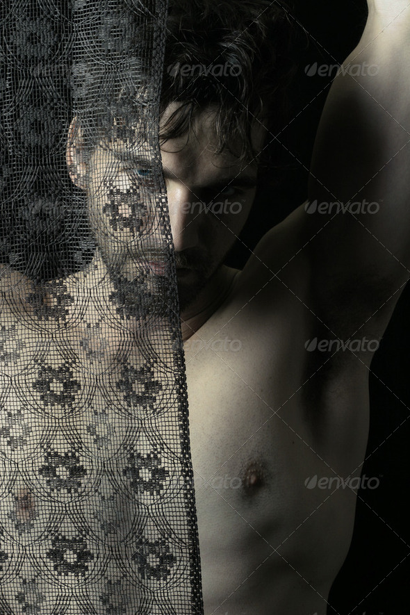 Sexy shadowy portrait of masculine male model behind dark lace - Stock Photo - Images