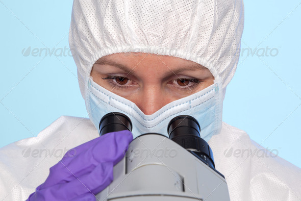 Female biochemist looking through microscope - Stock Photo - Images