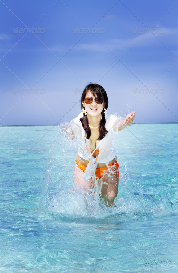 Beautiful fashion asian girl playing water in Maldive beach near the ocean - Stock Photo - Images