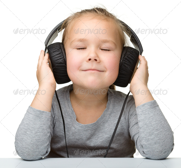Cute little girl enjoying music using headphones - Stock Photo - Images