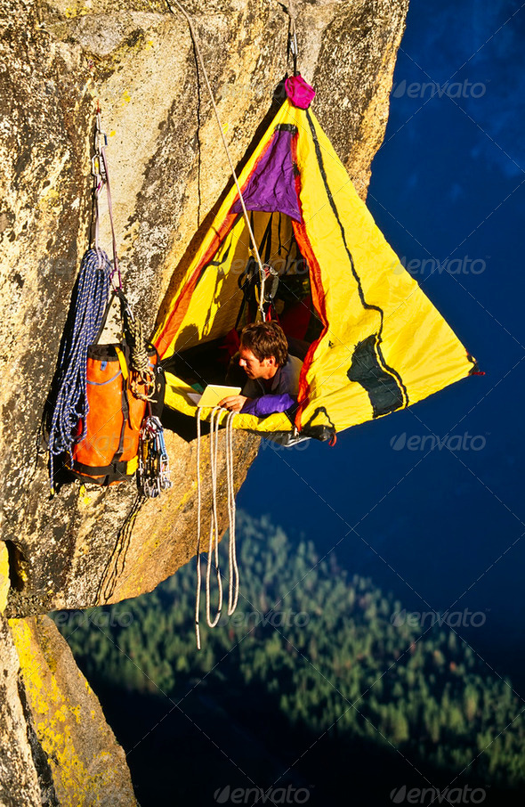 Rock climber bivouaced in a portaledge. - Stock Photo - Images