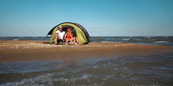 happy young couple sitting in tent seaside - Stock Photo - Images