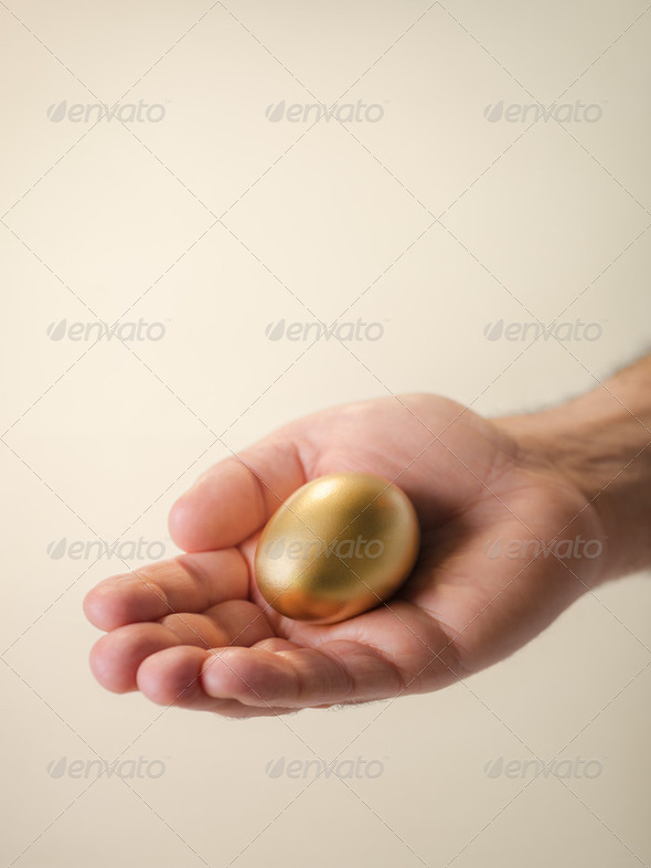Man showing golden eggs, symbol of money saving - Stock Photo - Images