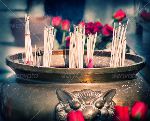 Buddhist shrine with smoking incense sticks and roses, cross-processed image , closeup