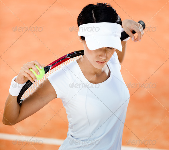 Woman keeps tennis racket and ball on her shoulders