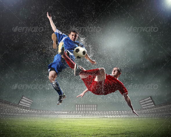 two football players striking the ball - Stock Photo - Images