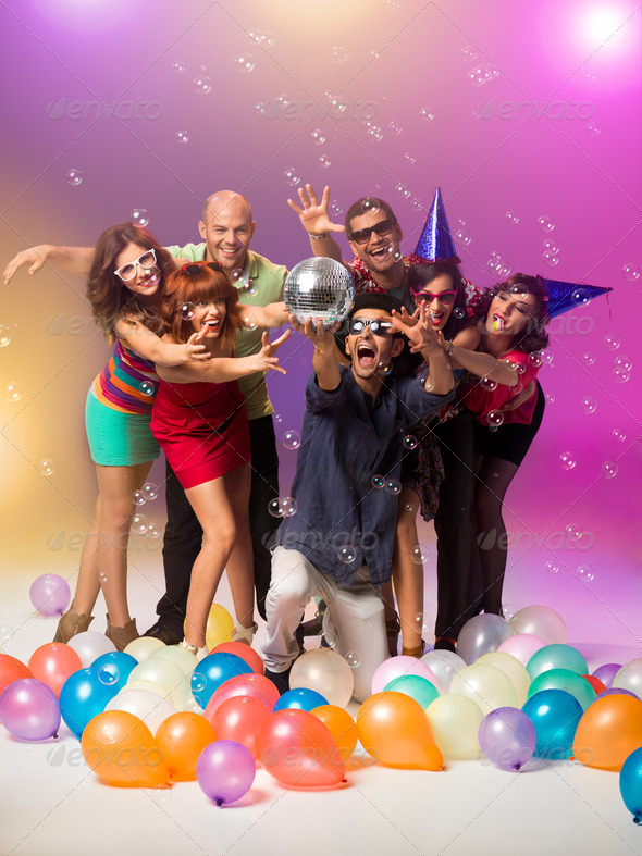 partying young people reaching for a disco ball - Stock Photo - Images