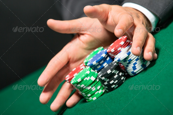 Poker player stakes “all in” pushing his chips forward. Risky entertainment of gambling