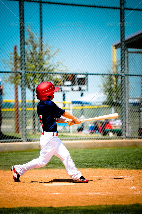Little league player swinging bat