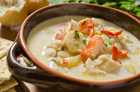 A steaming hot bowl of seafood chowder with lobster, clams, haddock, scallops, and potato.