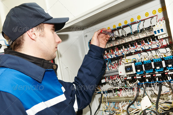 One electrician working on a industrial panel mounting, assembling, adjusting new voltage wiring