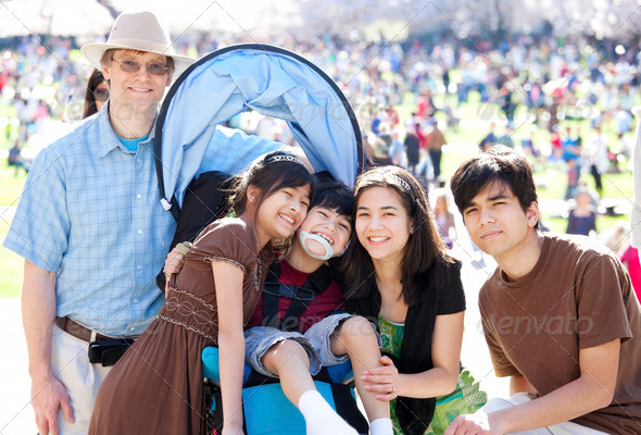 Large multiracial family in crowd with disabled child in wheelchair