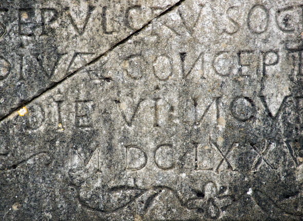 Closeup of antique text engraved on a flagstone.