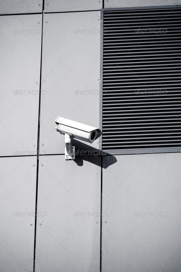 White security camera on office building, safety system. CCTV cam looking around and protecting a business