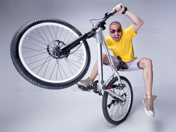 crazy boy on a dirt jump bike on grey background – wide studio shot