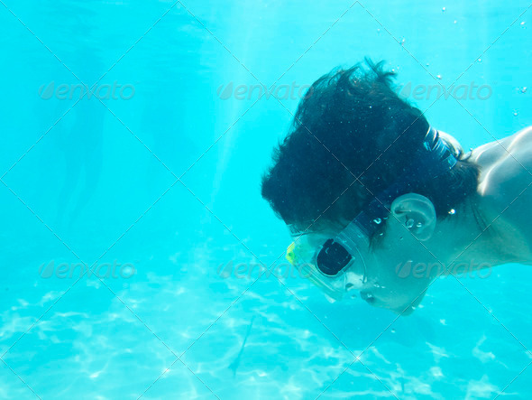 boy swimming underwater in the ocean, room for text in water area