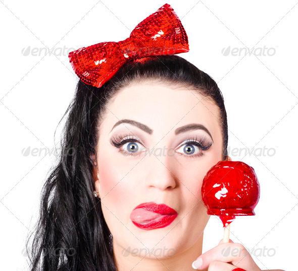Sweet pin-up girl eating a candy toffee apple - Stock Photo - Images