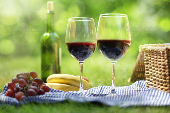 Picnic setting with red wine glasses bottle and picnic hamper basket