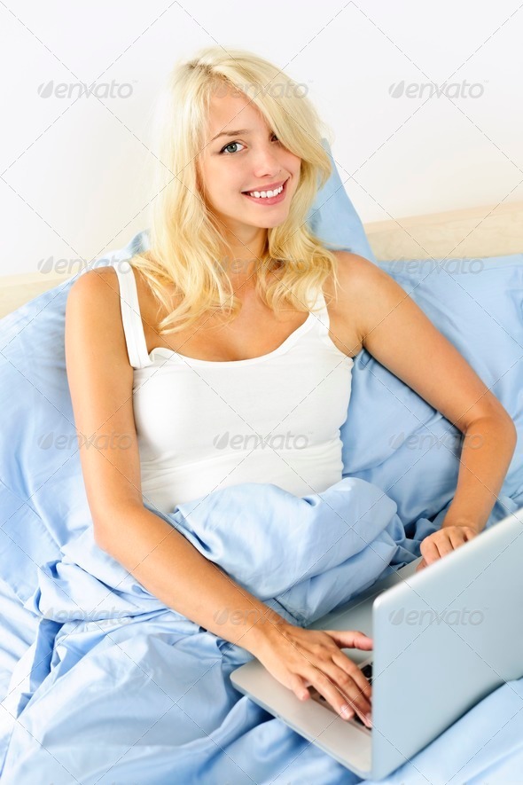 Woman sitting in bed with laptop computer - Stock Photo - Images