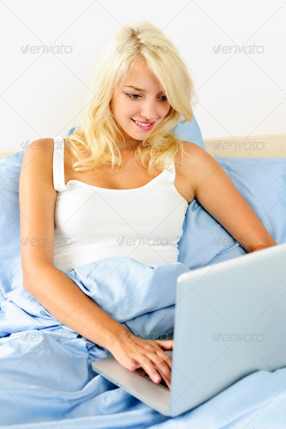 Woman sitting in bed with laptop computer - Stock Photo - Images