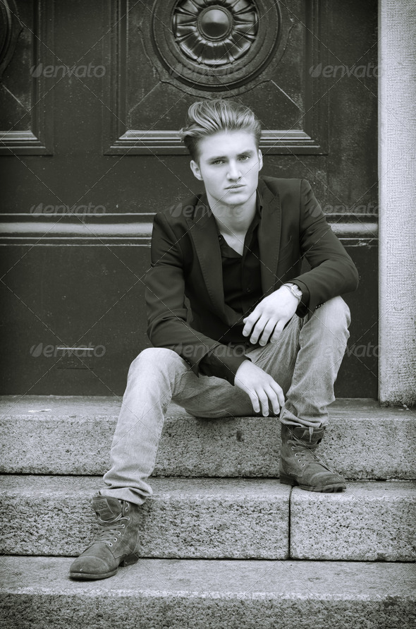 Attractive blue eyed, blond young man sitting on stair steps
