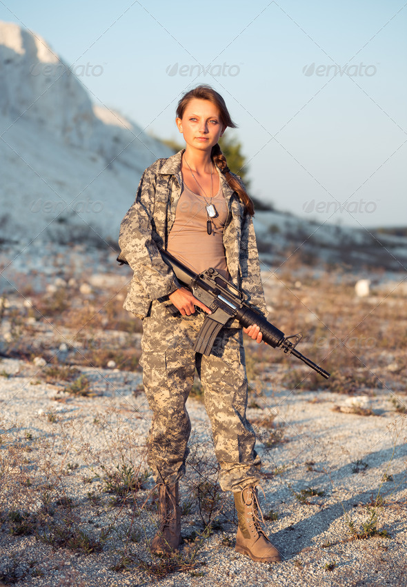 Young female soldier dressed in a camouflage with a gun in the l