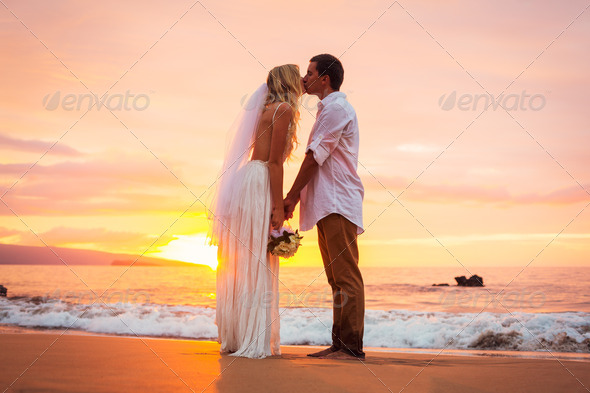 Married couple, bride and groom, kissing at sunset on beautiful