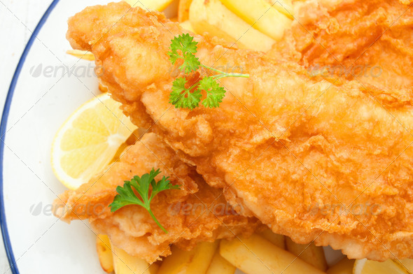 Two pieces of freshly fried fish with chips and a slice of lemon