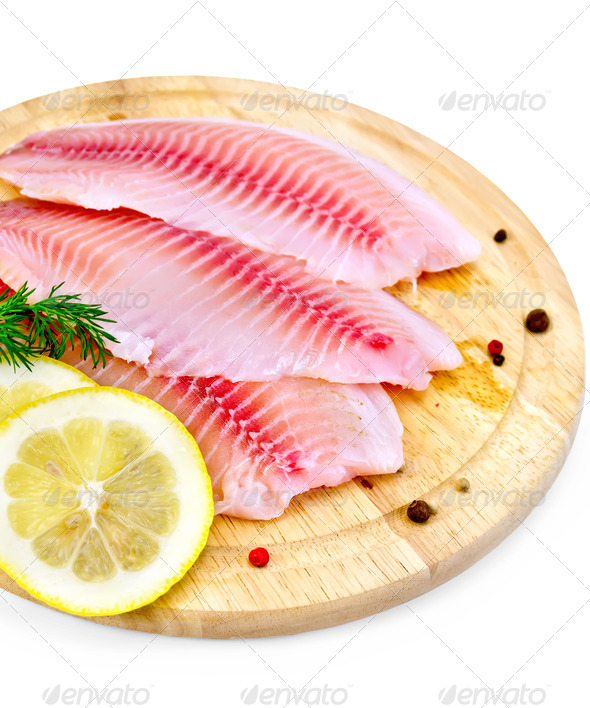 Fillets tilapia with lemon and dill on a board