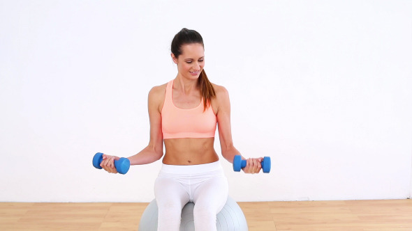 Fit Model Sitting On Exercise Ball Lifting Fit Model Sitting On Exercise Ball Lifting