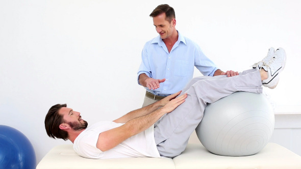 Physical Therapist Helping His Patient Do A Sit Up Physical Therapist Helping His Patient Do A Sit Up