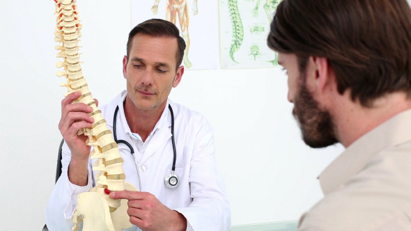 Doctor Showing His Patient A Spine Model Doctor Showing His Patient A Spine Model