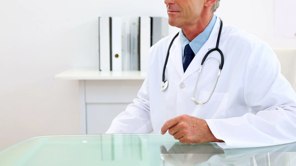 Mature Doctor Studying At Xray At His Desk Mature Doctor Studying At Xray At His Desk