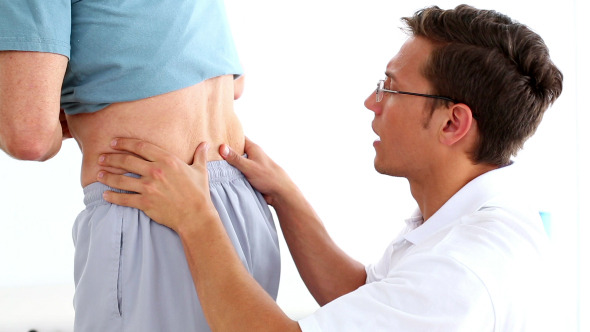 Physiotherapist Rubbing Mature Patients Lower Back Physiotherapist Rubbing Mature Patients Lower Back