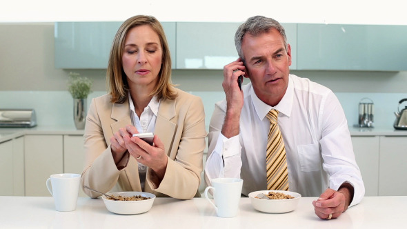 Couple Having Breakfast And Using Phones Couple Having Breakfast And Using Phones