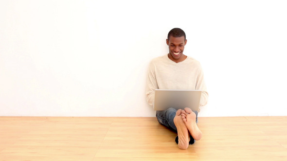 Smiling Man Using Laptop Sitting On The Floor Smiling Man Using Laptop Sitting On The Floor