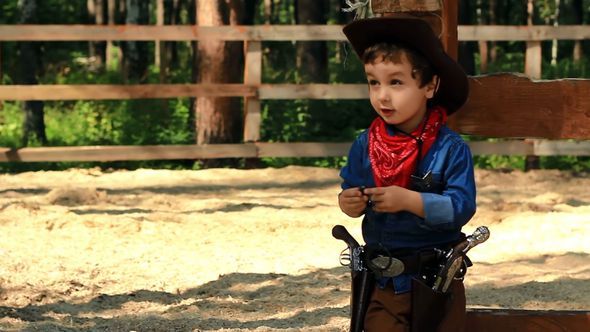 Little Cowboy Standing Near A Wooden Fence Little Cowboy Standing Near A Wooden Fence