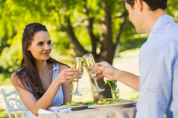 Smiling young couple toasting champagne flutes at an outdoor cafÃ© (Misc) Photo Download