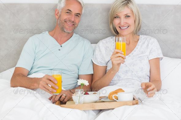 Portrait of happy mature couple having breakfast in bed at home (Misc) Photo Download